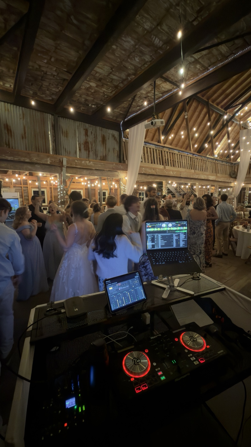 DJ controller and laptop overlooking guests dancing in the barn